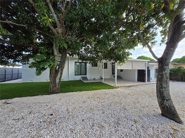 335 W 60th St, Hialeah, FL 33012 - view of front of house with gravel driveway, an attached carport, a patio area, and stucco siding