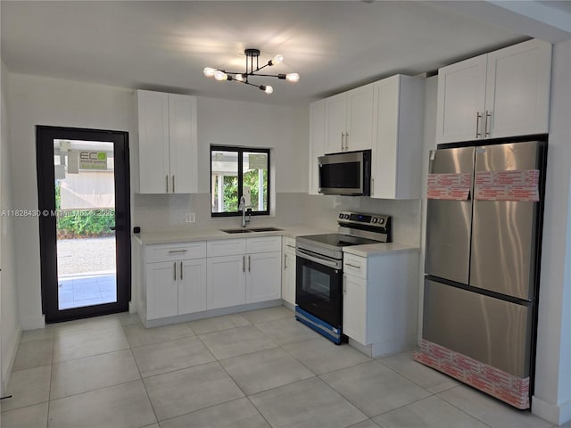 335 W 60th St, Hialeah, FL 33012 - kitchen with stainless steel appliances, light countertops, white cabinets, a chandelier, and light tile patterned flooring