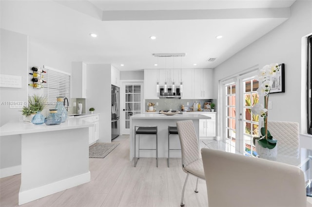 220 SW 113th Ter, Pembroke Pines, FL 33025 - kitchen featuring stainless steel appliances, a kitchen bar, white cabinets, light countertops, and tasteful backsplash
