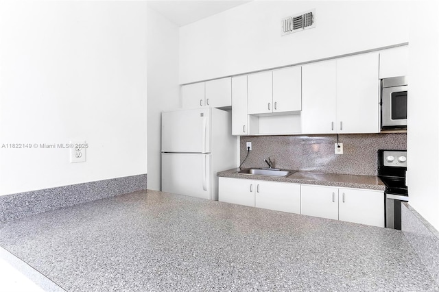 7400 W 20th Ave Unit 315, Hialeah, FL 33016 - kitchen featuring appliances with stainless steel finishes, tasteful backsplash, white cabinets, and a towering ceiling