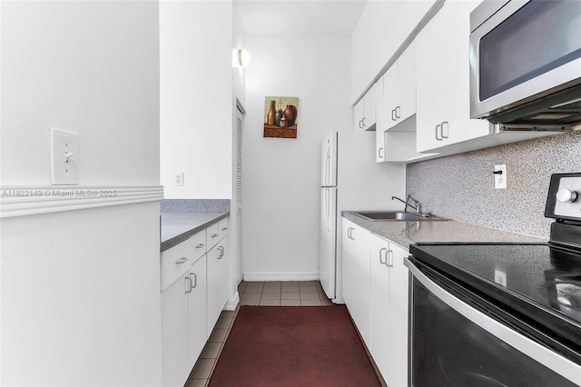 7400 W 20th Ave Unit 315, Hialeah, FL 33016 - kitchen featuring black range with electric stovetop, stainless steel microwave, dark tile patterned flooring, white cabinetry, and decorative backsplash