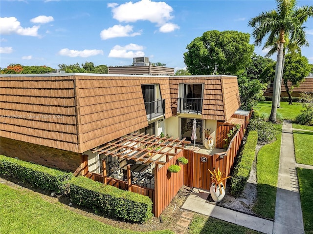9109 SW 20th St, Davie, FL 33324 - rear view of house featuring a balcony, brick siding, mansard roof, and a lawn