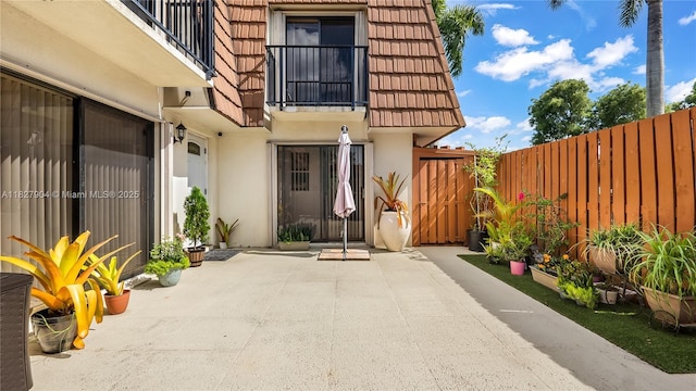 9109 SW 20th St, Davie, FL 33324 - view of exterior entry with stucco siding, a patio, a tile roof, mansard roof, and a balcony