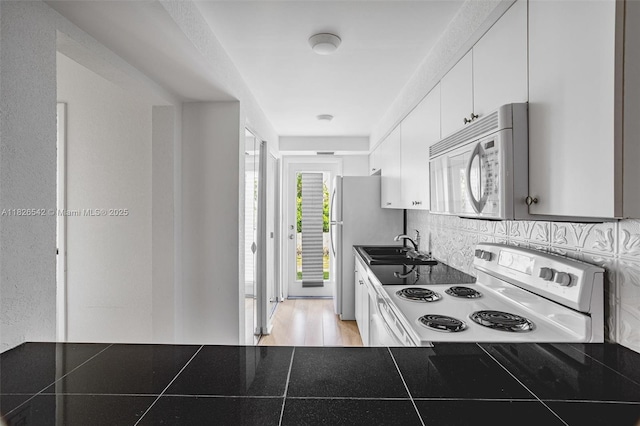 3931 Coral Springs Dr Unit 26, Coral Springs, FL 33065 - kitchen with white appliances, dark countertops, white cabinetry, and tasteful backsplash