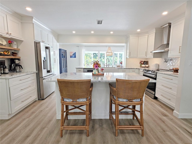 8994 SE Colony St, Hobe Sound, FL 33455 - kitchen with stainless steel appliances, wall chimney range hood, light wood-style floors, and recessed lighting