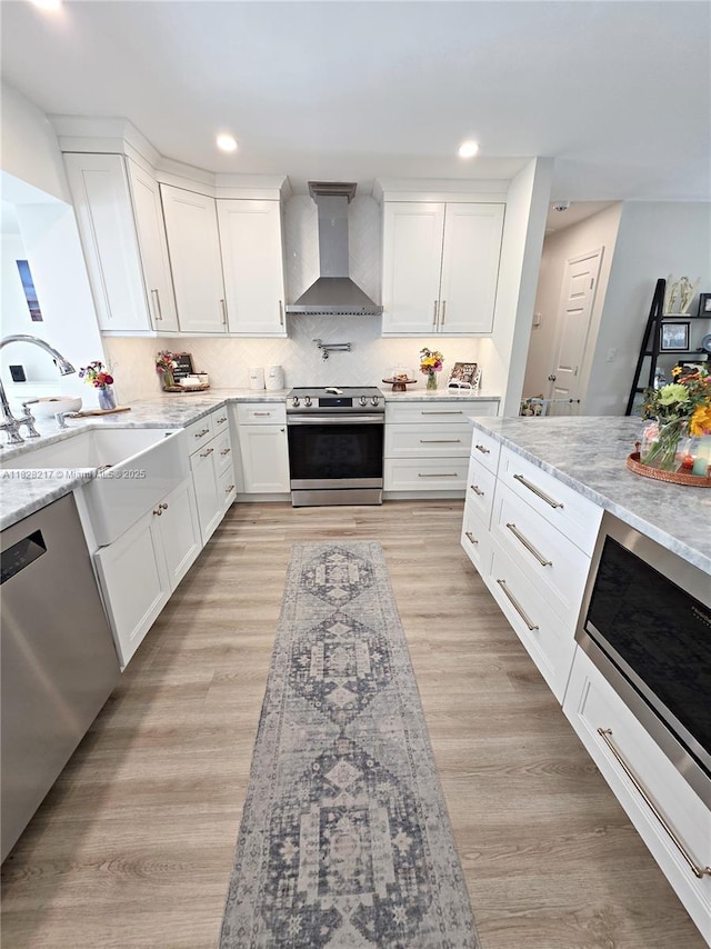 8994 SE Colony St, Hobe Sound, FL 33455 - kitchen with appliances with stainless steel finishes, wall chimney range hood, light stone countertops, white cabinetry, and recessed lighting