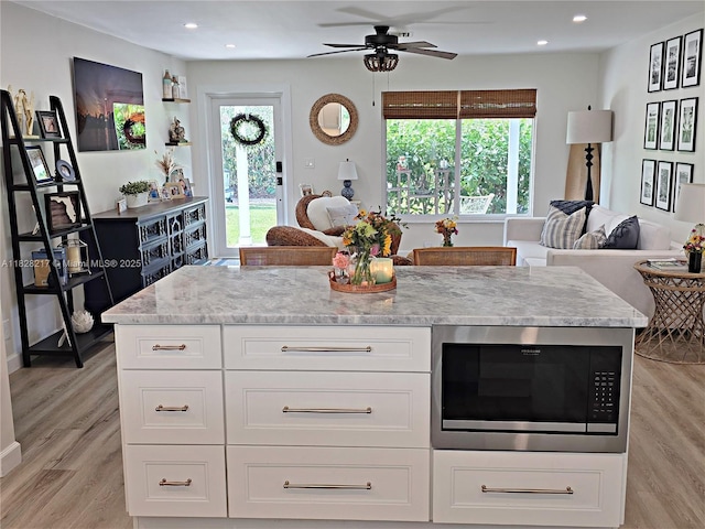 8994 SE Colony St, Hobe Sound, FL 33455 - kitchen with built in microwave, open floor plan, light stone countertops, light wood finished floors, and a ceiling fan