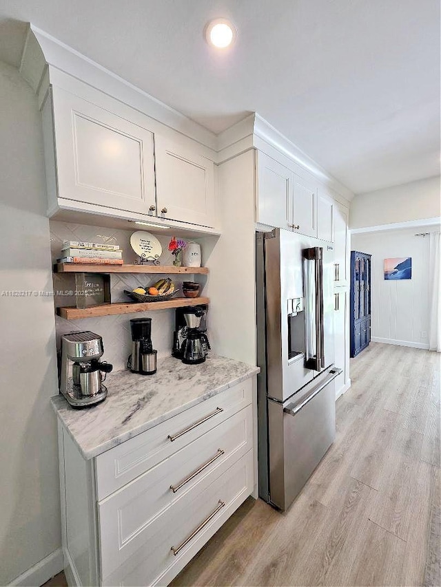 8994 SE Colony St, Hobe Sound, FL 33455 - kitchen with stainless steel refrigerator with ice dispenser, light wood finished floors, white cabinetry, and light stone countertops