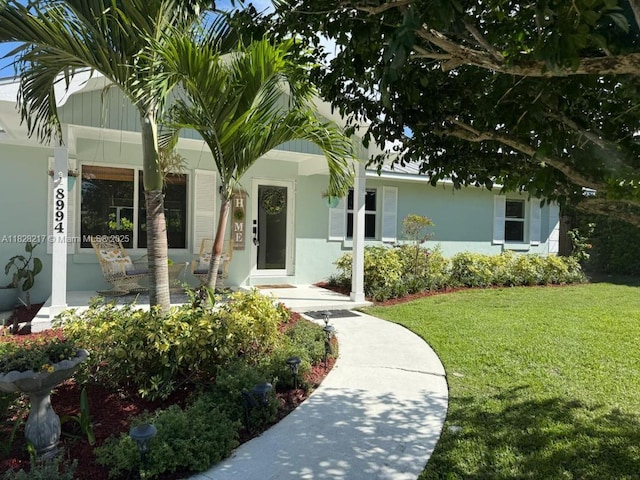 8994 SE Colony St, Hobe Sound, FL 33455 - entrance to property featuring a lawn, stucco siding, and covered porch