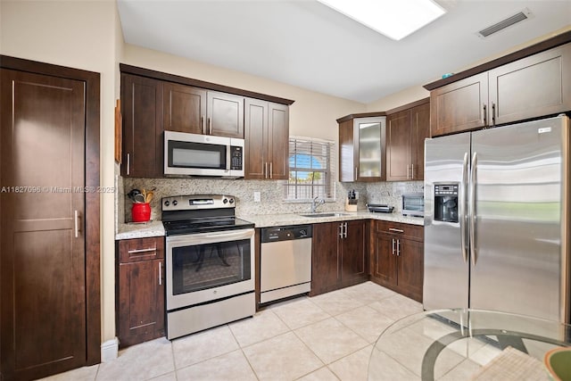 1115 SW 180th Ter, Pembroke Pines, FL 33029 - kitchen with appliances with stainless steel finishes, backsplash, dark brown cabinetry, light tile patterned floors, and glass insert cabinets