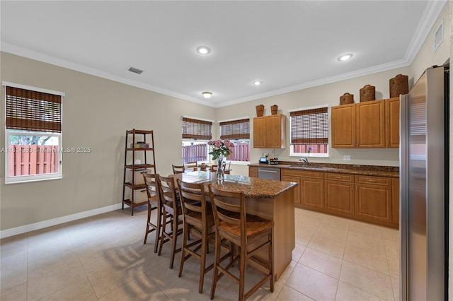 14141 SW 54th St, Miramar, FL 33027 - kitchen with stainless steel appliances, a kitchen breakfast bar, ornamental molding, a center island, and brown cabinets