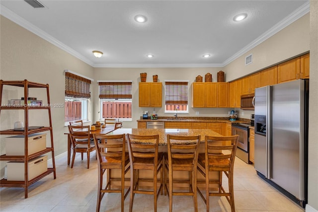 14141 SW 54th St, Miramar, FL 33027 - kitchen featuring appliances with stainless steel finishes, ornamental molding, light tile patterned floors, a center island, and a breakfast bar