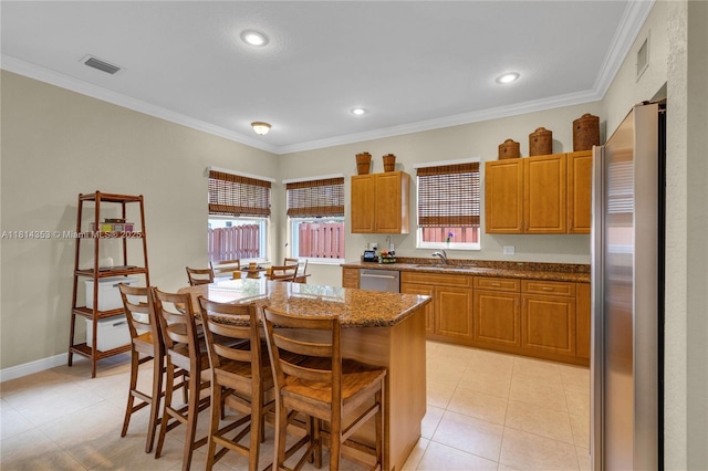 14141 SW 54th St, Miramar, FL 33027 - kitchen with stainless steel appliances, a center island, a breakfast bar, dark stone counters, and ornamental molding