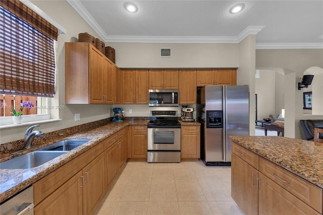 14141 SW 54th St, Miramar, FL 33027 - kitchen featuring appliances with stainless steel finishes, ornamental molding, dark stone counters, brown cabinets, and light tile patterned floors