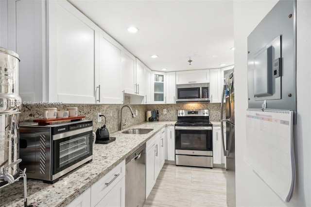 2401 Collins Ave Unit 1011, Miami Beach, FL 33140 - kitchen featuring appliances with stainless steel finishes, light stone countertops, white cabinets, glass insert cabinets, and recessed lighting