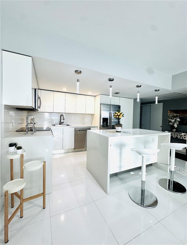 19390 Collins Ave Unit 911, Sunny Isles Beach, FL 33160 - kitchen featuring appliances with stainless steel finishes, light countertops, a breakfast bar area, white cabinets, and a center island