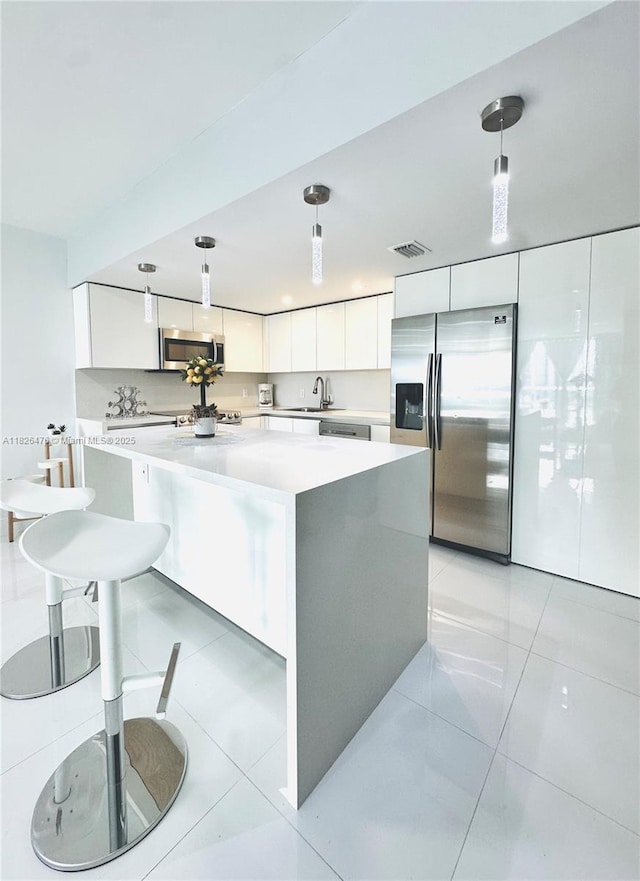 19390 Collins Ave Unit 911, Sunny Isles Beach, FL 33160 - kitchen with appliances with stainless steel finishes, white cabinetry, a center island, light countertops, and hanging light fixtures