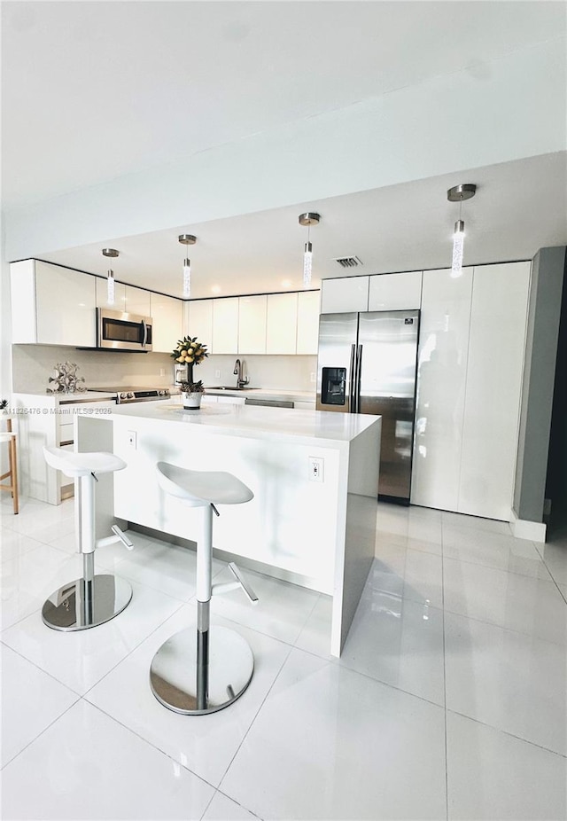 19390 Collins Ave Unit 911, Sunny Isles Beach, FL 33160 - kitchen featuring appliances with stainless steel finishes, white cabinetry, a kitchen island, and light countertops