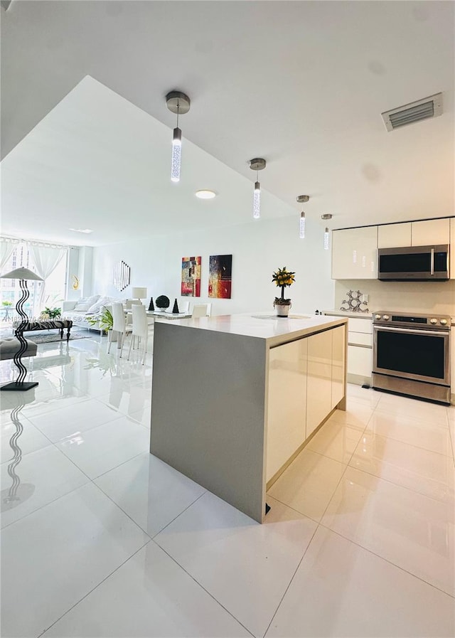 19390 Collins Ave Unit 911, Sunny Isles Beach, FL 33160 - kitchen with appliances with stainless steel finishes, white cabinetry, hanging light fixtures, and light countertops