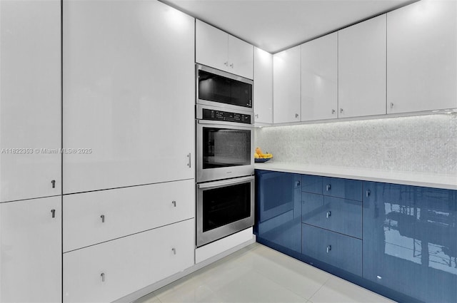 3900 Galt Ocean Dr Unit 506, Fort Lauderdale, FL 33308 - kitchen featuring appliances with stainless steel finishes, light countertops, white cabinets, tasteful backsplash, and blue cabinets