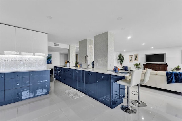 3900 Galt Ocean Dr Unit 506, Fort Lauderdale, FL 33308 - kitchen featuring blue cabinetry, light tile patterned flooring, a kitchen breakfast bar, open floor plan, and light countertops