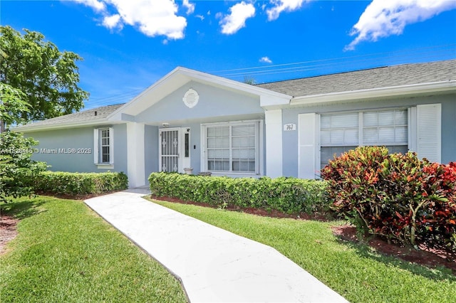 767 SE 22nd Dr, Homestead, FL 33033 - view of front of house with a front yard, a shingled roof, and stucco siding