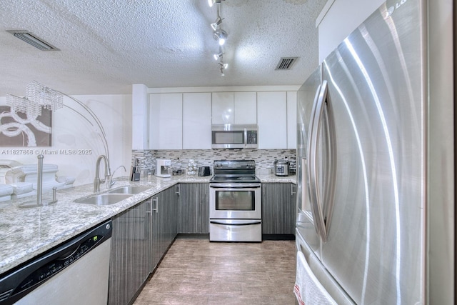 10000 SW 147th Ct, Miami, FL 33196 - kitchen featuring appliances with stainless steel finishes, gray cabinetry, light wood-style flooring, white cabinets, and backsplash