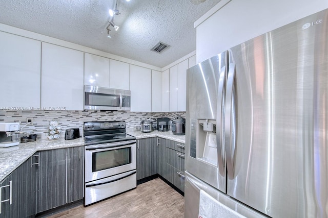 10000 SW 147th Ct, Miami, FL 33196 - kitchen with stainless steel appliances, gray cabinets, light wood-style floors, tasteful backsplash, and white cabinetry