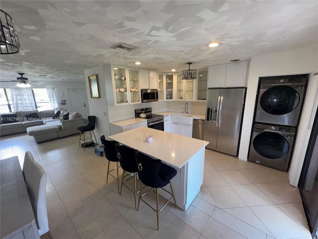 3370 Beau Rivage Dr, Pompano Beach, FL 33064 - kitchen with stainless steel appliances, stacked washer / drying machine, a breakfast bar, light countertops, and white cabinets