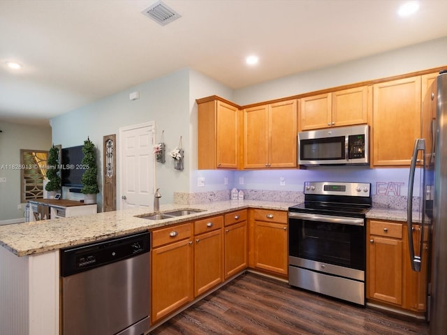 5656 NW 58th Ln, Tamarac, FL 33319 - kitchen featuring appliances with stainless steel finishes, a peninsula, dark wood-style flooring, light stone countertops, and recessed lighting