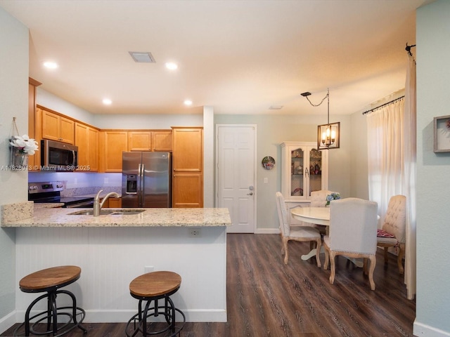 5656 NW 58th Ln, Tamarac, FL 33319 - kitchen with appliances with stainless steel finishes, dark wood-style floors, a peninsula, a kitchen bar, and light stone countertops