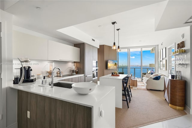 2900 NE 7th Ave Unit 2303, Miami, FL 33137 - kitchen featuring light countertops, modern cabinets, a peninsula, hanging light fixtures, and a kitchen island