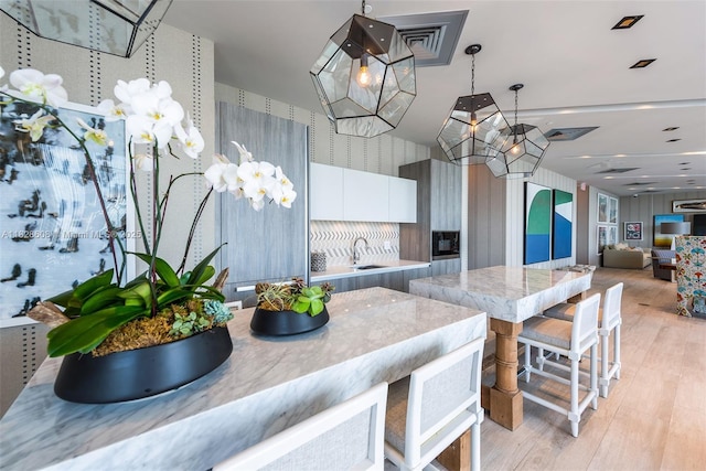 2900 NE 7th Ave Unit 2303, Miami, FL 33137 - kitchen featuring modern cabinets, a chandelier, wallpapered walls, light wood-style floors, and white cabinets