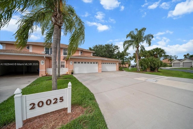 20025 Lake Vista Cir Unit 6B, Lehigh Acres, FL 33936 - view of front of house featuring stucco siding, driveway, a garage, and a front yard