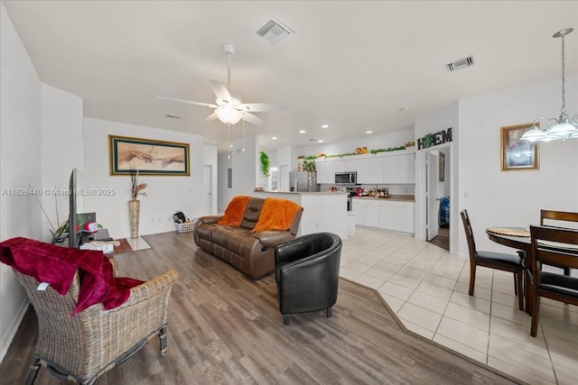20025 Lake Vista Cir Unit 6B, Lehigh Acres, FL 33936 - living room featuring a ceiling fan, light wood finished floors, and a chandelier