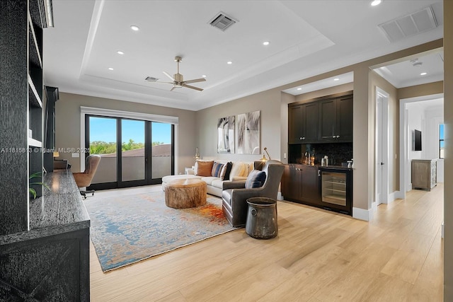 16675 C 24 Canal Rd, Port St Lucie, FL 34987 - living room with a raised ceiling, wet bar, beverage cooler, a ceiling fan, and light wood finished floors