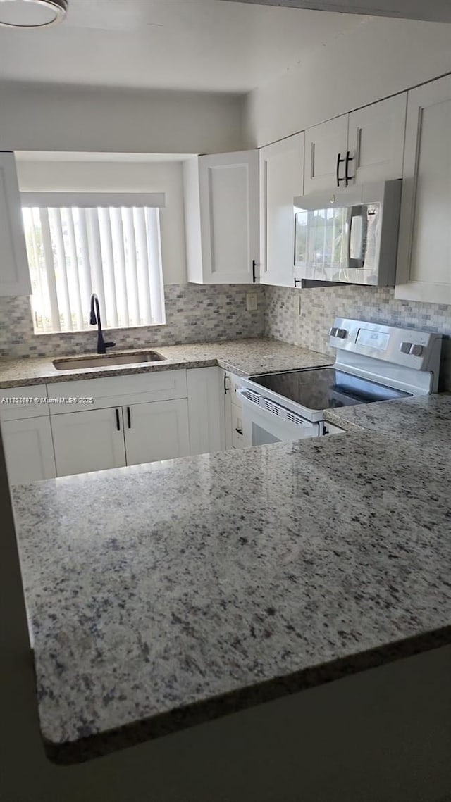 14902 SW 82nd Ln Unit 13-101, Miami, FL 33193 - kitchen with white appliances, white cabinets, light stone countertops, and decorative backsplash