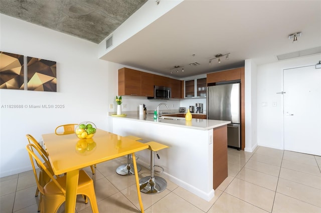 3250 NE 1st Ave Unit 911, Miami, FL 33137 - kitchen with stainless steel appliances, a peninsula, light countertops, rail lighting, and light tile patterned floors