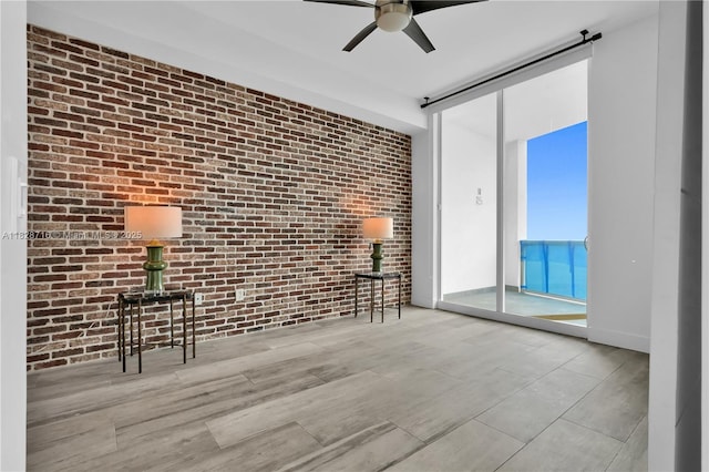 725 NE 22nd St Unit 16A, Miami, FL 33137 - spare room featuring brick wall, ceiling fan, a barn door, wood finished floors, and expansive windows