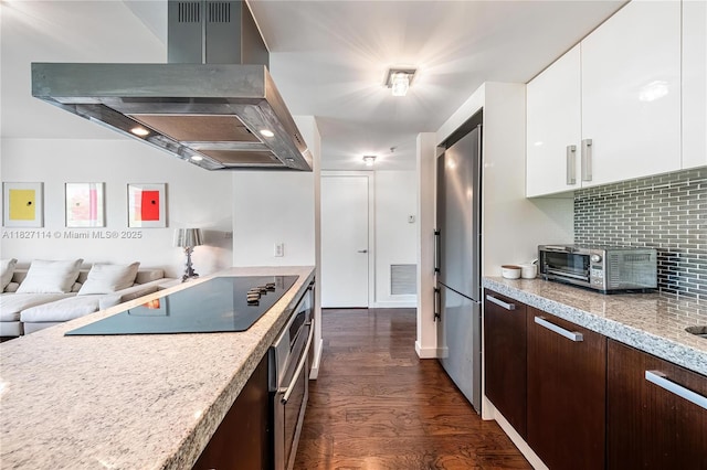 720 NE 62nd St Unit 403, Miami, FL 33138 - kitchen featuring wall chimney range hood, dark brown cabinetry, dark wood-style flooring, white cabinetry, and tasteful backsplash