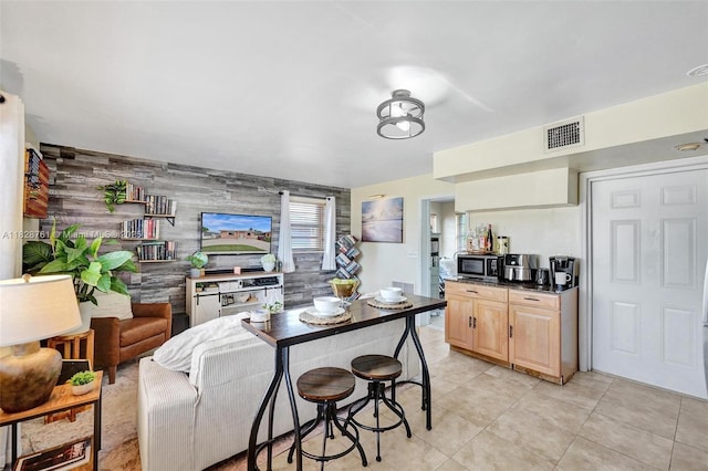 2435 Wilson St, Hollywood, FL 33020 - kitchen featuring stainless steel microwave, light tile patterned floors, dark countertops, an accent wall, and light brown cabinetry