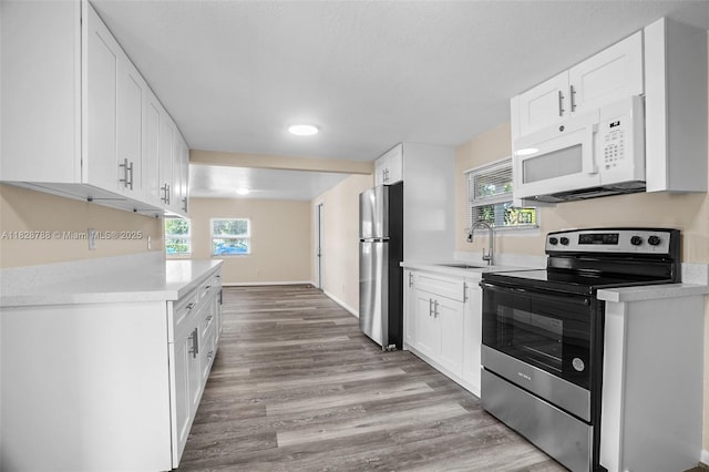 212 SW 11th St, Dania Beach, FL 33004 - kitchen featuring appliances with stainless steel finishes, light wood-style floors, light countertops, and white cabinetry
