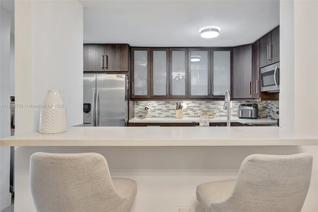 9255 SW 125th Ave Unit 108R, Miami, FL 33186 - kitchen featuring appliances with stainless steel finishes, dark brown cabinets, glass insert cabinets, and backsplash