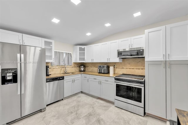 6601 Branch St, Hollywood, FL 33024 - kitchen featuring appliances with stainless steel finishes, backsplash, glass insert cabinets, white cabinetry, and lofted ceiling