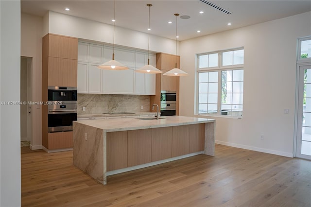 7605 SW 71st Ave, Miami, FL 33143 - kitchen featuring light wood finished floors, black electric stovetop, a large island with sink, backsplash, and recessed lighting