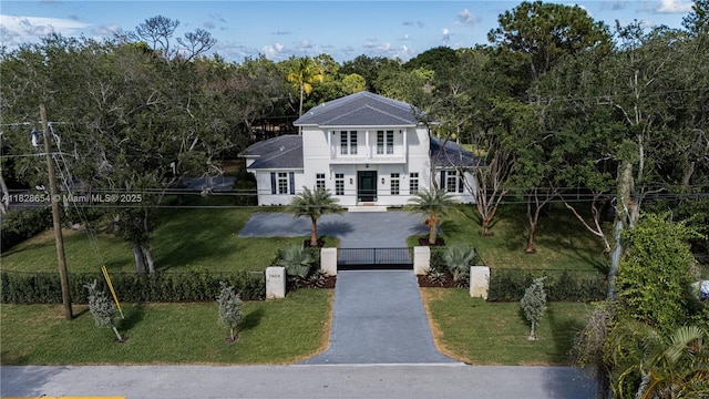 7605 SW 71st Ave, Miami, FL 33143 - neoclassical / greek revival house with asphalt driveway, a gate, a garage, a fenced front yard, and a wooded view