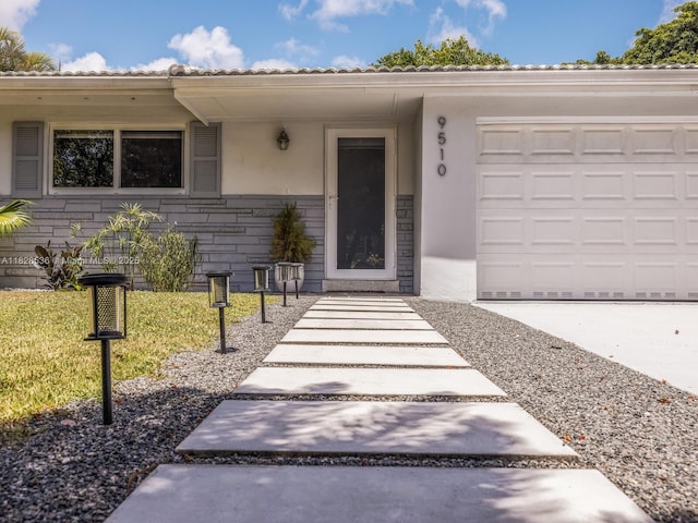 9510 NW 1st Ave, Miami Shores, FL 33150 - view of exterior entry with stucco siding, an attached garage, and stone siding