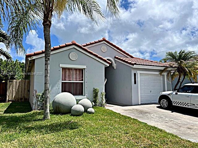 1988 SE 12th St, Homestead, FL 33035 - mediterranean / spanish house featuring concrete driveway, a front yard, a garage, stucco siding, and a tiled roof