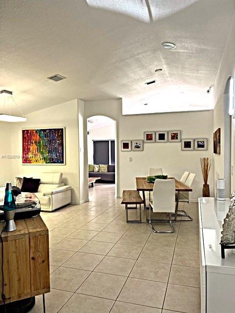1988 SE 12th St, Homestead, FL 33035 - dining room with tile patterned flooring, arched walkways, and a textured ceiling