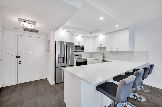 600 Three Islands Blvd Unit 1016, Hallandale Beach, FL 33009 - kitchen featuring stainless steel appliances, a peninsula, a breakfast bar area, dark wood finished floors, and white cabinetry